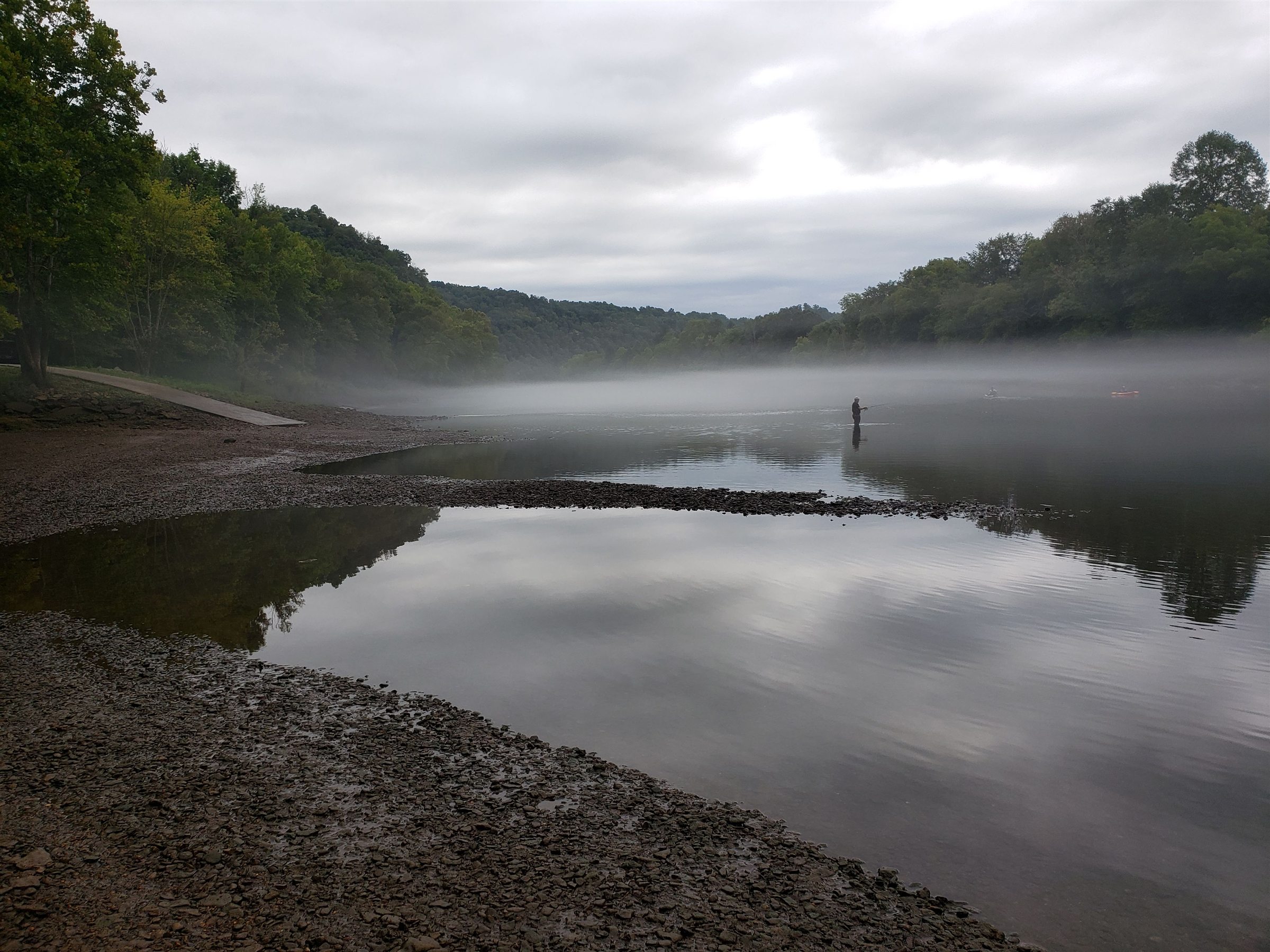 A quiet river covered in a low layer of morning fog
