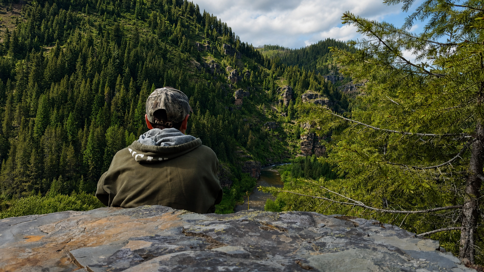 Hayden looking out across a forested river canyon
